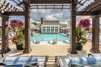 A pool surrounded by a wooden pergola and lounge chairs